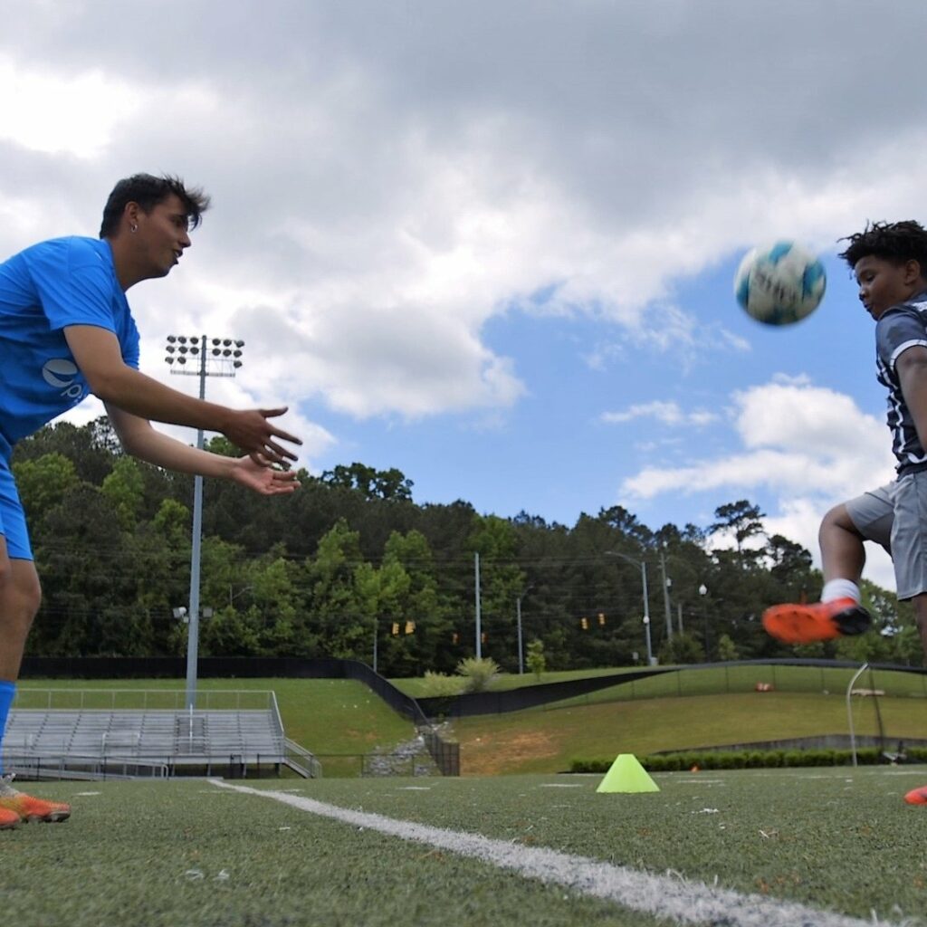 An FC Birmingham Player Encourages A BCS Student During A Soccer Drill At The BCS Let's Move Community Huddle.